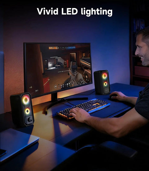 Desktop Computer Speakers Hi Res Stereo Pair With Dual 5W Full Range Drivers USB Powered And 3.5mm AUX Input Volume Knob 6 RGB Light Modes next to a gaming monitor.