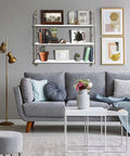 Living room with dope floating shelves, gold wall shelf for bathroom and kitchen, sleek minimalist vibe above gray couch.