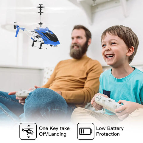 Father and son flying SYMA S107H Mini RC Helicopter indoors using remote controls, showcasing one-key takeoff and landing feature.