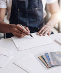 Person using Bulk Card Shipping Kit For Trading Cards And Sports Cards, 425 Pcs Bundle with card shields and envelopes on a table.