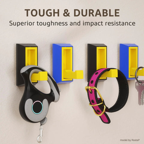 Front view of wall-mounted yellow hooks on blue and black brackets holding a headset, pink collar, and keys.