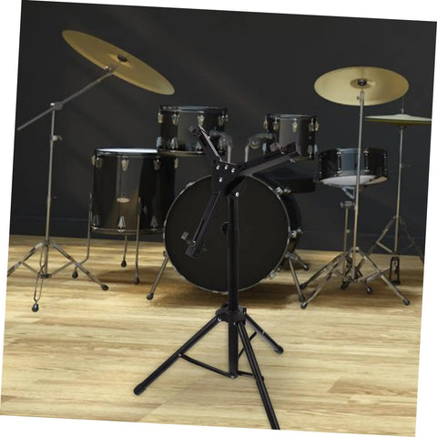 Adjustable Snare Drum Stand With Practice Pad Mount Alloy Build designed for stability with a sleek black finish, set near a drum kit.
