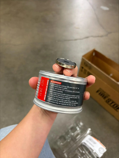Close-up of Automatic Fire Suppressor For Residential Kitchens, Direct Flame Activated, held in hand, showing label details.