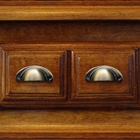 Snag A Win With These Next Level 4 Piece Iron Cup Pulls That Bring Fresh Vintage Shell Energy To Your Kitchen Cabinets Or Dresser Drawers While Delivering Insanely Sturdy Performance And A Sleek Brushed Bronze Look That Makes Your Space Pop - Close-up of two brushed bronze iron cup pulls on wooden drawers.