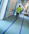Workmen installing Aqua Shield Surface Protector 10 Mil 36 Inch By 100 Foot Heavy Duty Protective Film in a construction hallway.