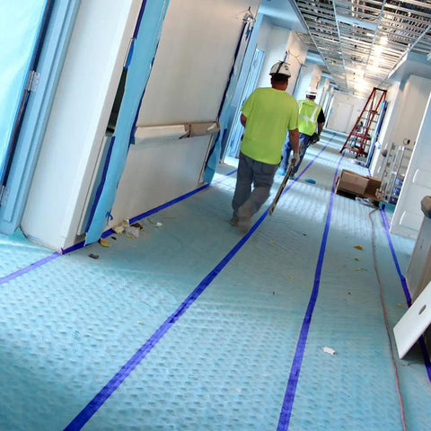 Workmen installing Aqua Shield Surface Protector 10 Mil 36 Inch By 100 Foot Heavy Duty Protective Film in a construction hallway.