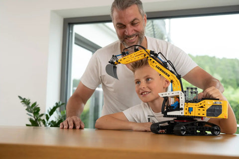 Father and child with Liebherr R938 Pneumatic Excavator Kit 689 Piece Realistic Builder Model With Pneumatic System Manual Valves And Flow Regulators Ideal For Gearheads 10 And Up Great For Kids Teens And Adults Who Love Engineering.