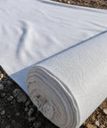 Heavy Duty Polyester Ground Cover Mat With Built Like A Tank Weed Barrier And Water Permeable Drainage Design For Outdoor Landscaping Playground Surface Base Foundation Underlayment in rolled position on soil.