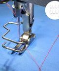 Close-up of an industrial sewing machine with 8 Pcs Industrial Sewing Machine Safety Needle Finger Guards That Protect Your Hands While You Sew Easy Install Shields For Heavy Duty Stitching Reducing Needle Injuries And Frustration On Every Project installed, showing the needle and red thread on blue fabric.