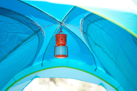 Orange 30 Day 1000 Lumen LED Lantern With Glow In The Dark Power Button And Built In Hook hanging inside blue camping tent.
