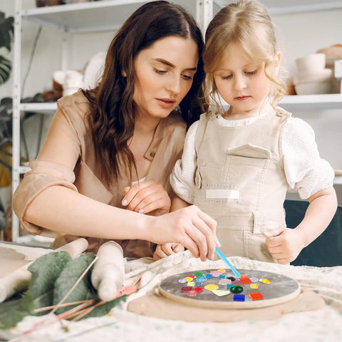 Woman and child using 28 Piece Stepping Stone Mold Kit With Round Concrete Molds And Mosaic Tiles And Carving Tools for DIY.