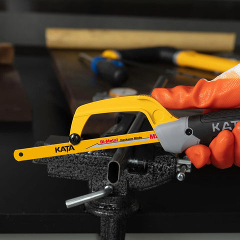 Front view of KATA mini hacksaw for metal, yellow aluminum frame with black handle cutting a metal tube in a vise