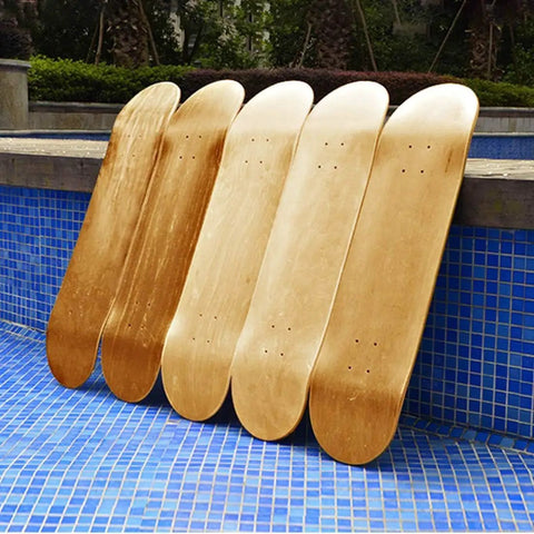 Blank Maple Skateboard Decks Set Of 3, 31 X 8 Inches, resting by a blue tiled poolside, showcasing their double tail design.