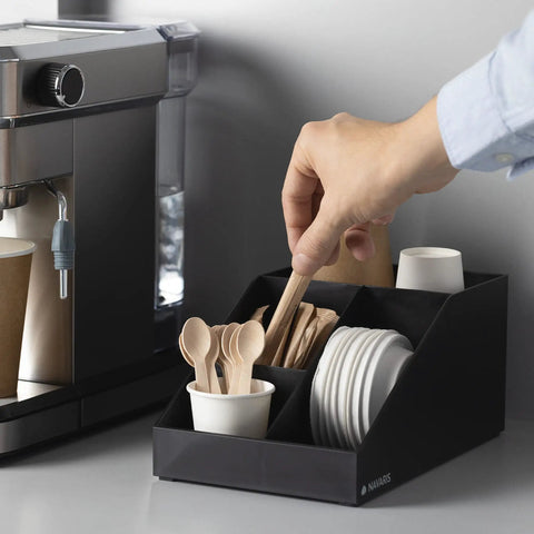 Coffee Station Organizer With 4 Compartments Perfect For Storing Coffee Pods Sugar Creamer Stirrers And Tea Bags On Your Office Or Kitchen Countertop For Quick Grab And Go Access And Neat Countertop Organization in use with a hand reaching for a stirrer.