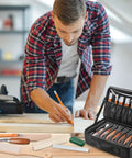 Man using All In One Wood Carving Kit For Beginners 35 Piece Set with whittling knives, chisels, and storage bag in home workshop.