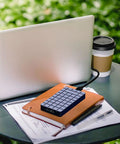 No Sweat M2 NVMe SSD Enclosure Rugged Aluminum USB4 External Drive Case with papers and laptop in outdoor setting.