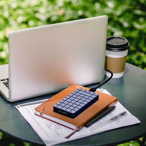No Sweat M2 NVMe SSD Enclosure Rugged Aluminum USB4 External Drive Case with papers and laptop in outdoor setting.