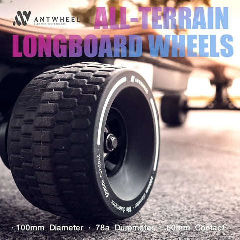 Close-up of all-terrain longboard wheels 100mm 65mm urethane 78A high rebound, attached to an electric skateboard on pavement.