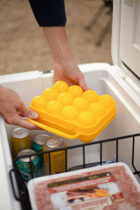 Person placing 12 Count Camping Egg Keeper For Outdoor Cooking And Travel Durable Compact Lightweight Storage Container in cooler.