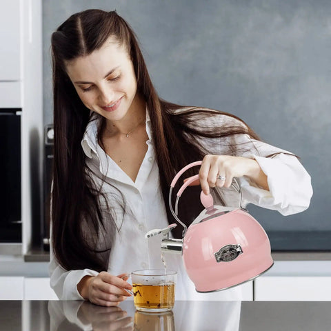 Woman pouring from a pink 2.6 Quart Stainless Steel Whistling Tea Kettle for Stovetop and Induction into a glass cup.