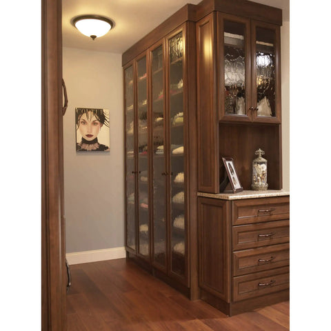 Aspen Round Cabinet Knob In Light Bronze Finish, installed on tall wooden cabinets with decorative glass doors in elegant room.