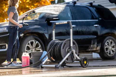 Woman using 200 Foot Heavy Duty Aluminum Upright Hose Reel With Rust Proof Frame Leak Proof Brass Connections to wash car