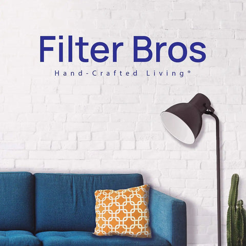 Modern living room with blue sofa, decorative cushion, floor lamp, brick wall, and text 'Filter Bros Hand-Crafted Living'