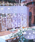 Garden wedding setup with Two Pack Of 33 Feet Solar String Lights With 100 LEDs Each, illuminating a rustic table.