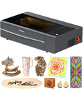 Front view of gray xTool P2S 55W CO2 laser cutter with top window; assorted wood, acrylic, and leather pieces.
