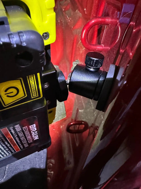 Magnetic camera mount with rubber-coated neodymium magnet and mini ball head securely attached to a red metal surface.