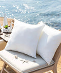Premium Outdoor Pillow Inserts Pack Of 2 Square 18 By 18 Inches Water Resistant Polyester Throw Pillows on a chair outdoors