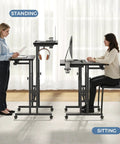 Split Top Rolling Standing Desk With Adjustable Height From 28 To 45 Inches Manual Lift Mobile Laptop Desk On Wheels Sit Stand Office Table For Home Office Black, showing sitting and standing use with two people and equipment on desks