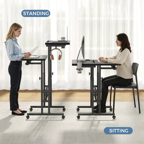 Split Top Rolling Standing Desk With Adjustable Height From 28 To 45 Inches Manual Lift Mobile Laptop Desk On Wheels Sit Stand Office Table For Home Office Black, showing sitting and standing use with two people and equipment on desks