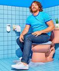 Man using touchless toilet paper foam dispenser kit with wall-mounted setup, next to pink toilet, in a blue tiled bathroom.