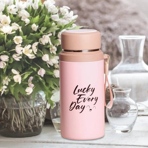 Pink 800ml insulated water bottle with tea infuser on table, "Lucky Every Day" text, leakproof vacuum-sealed stainless steel flask