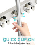 Hand placing mop into Over The Door Mop And Broom Holder No Drill Wall Mount With Four Slots And Four Hooks Wood Tool Hanger.