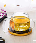 Electric Coffee Mug Warmer Heats Your Daily Brew Piping Hot With Precise Auto Timer And Dual Heat Settings Built From Scratch Safe Tempered Glass holding a glass mug with tea on a gold base.