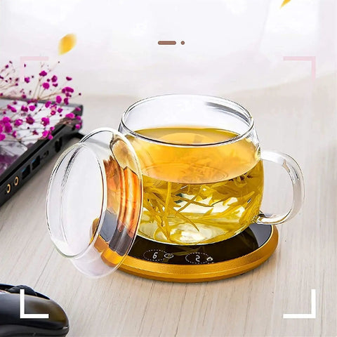 Electric Coffee Mug Warmer Heats Your Daily Brew Piping Hot With Precise Auto Timer And Dual Heat Settings Built From Scratch Safe Tempered Glass holding a glass mug with tea on a gold base.