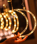 Hand holding moon-shaped Ramadan Curtain Fairy Lights With Remote, 138 LED 8.2ft By 3.2ft, warm white glow, chill vibes