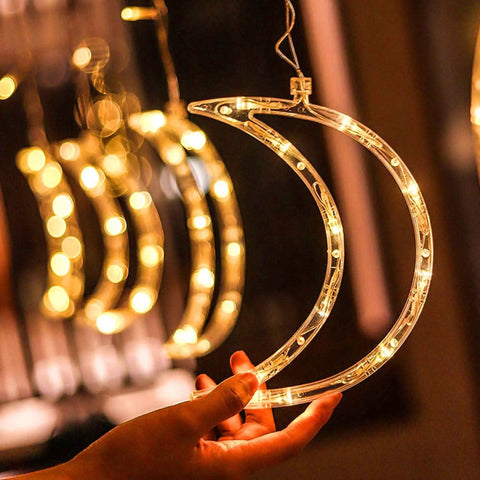 Hand holding moon-shaped Ramadan Curtain Fairy Lights With Remote, 138 LED 8.2ft By 3.2ft, warm white glow, chill vibes