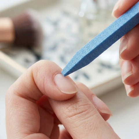 Using Stone Nail File Set With Pumice Stick And Cuticle Pusher For Fingernails And Toenails Care on a person's cuticle.
