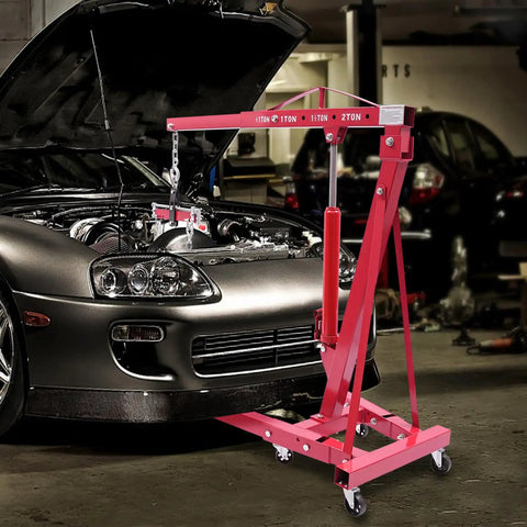 Heavy Duty Folding Hydraulic Engine Hoist Stand Built With Hella Tough Carbon Steel and Zero Sweat Operation For Easy Garage Work and Quick Storage Solutions lifting engine over a car.