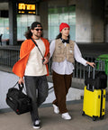 People at airport terminal with Carry On Duffel Bag For Air Travel And Personal Item, softside 16-inch black, and yellow suitcase