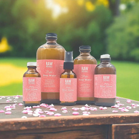 Display of One Ingredient Pure Organic Rose Water Hydrosol Mist in various glass bottles on a wooden table surrounded by petals