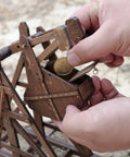 Mini Counterweight Trebuchet Model Kit for Adults, 3D Wooden Puzzle Siege Engine, DIY STEM Project, Tabletop Toy, Alder Veneer Plywood Build, Ages 14 Plus, Totally Fun Historical Replica. Hands loading wooden trebuchet.