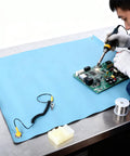 Fabater anti-static ESD mat on blue thermoplastic work surface with grounding wire for PCB repair and PC building.