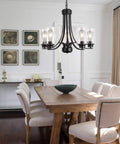 Five Light Matte Black Farmhouse Industrial Chandelier With Clear Glass Shades over dining room table with modern decor.