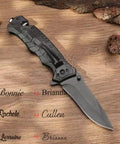 Black Serrated Folding Knife With Dual Edge Design placed on wooden background, showing closed blade and textured handle