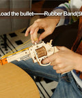 Person loading rubber bands into Dope 3D Wooden Puzzle And Mechanical Model Kit For DIY Builders With Multiplayer Target Shooting Game