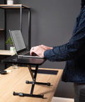 Black 28 Inch Standing Desk Converter Sit To Stand Monitor Riser With Scissor Lift Height Adjustment in a home office setup